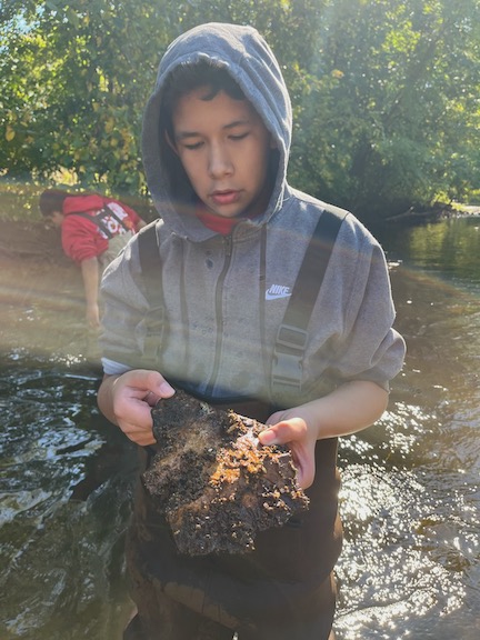 photo of student studying rock with moss